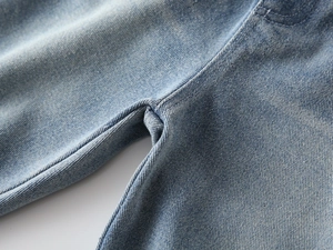 Close-up of reinforced double-stitched crotch seam on light blue cotton denim jeans