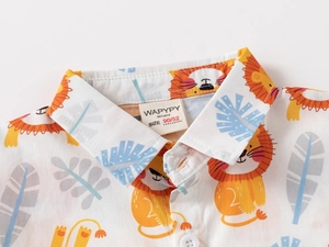 Close-up of baby shirt collar featuring orange lion and tropical leaf digital prints