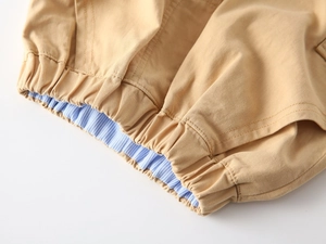 Dettaglio dei pantaloncini kaki da ragazzo con elastico in vita a righe e cuciture
