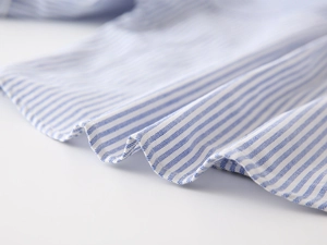 Détail de chemise en coton à rayures bleues et blanches montrant le tissu et les coutures