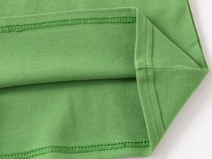 Vue détaillée de la texture en maille piquée verte et double couture sur ce polo pour enfants