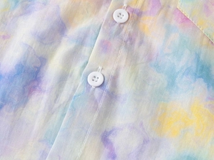 Detailed macro view of white four-hole buttons and colorful tie-dye print on cotton shirt