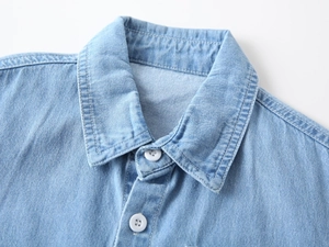 Detailed view of kids denim shirt collar with white buttons and fine double stitching