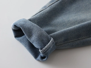 Detail of classic blue denim jeans hem featuring rolled cuffs and precise white stitching
