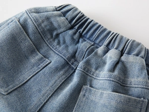 Detail of children's washed denim jeans showing elastic waistband and back pockets