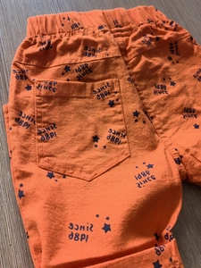 Kids orange drawstring shorts featuring black star prints and vintage 1989 lettering