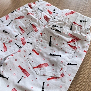 Detail view of boys white cotton shorts with elastic waist and red bottle pattern