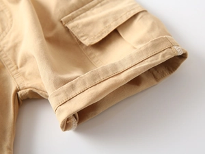 Dettaglio dei pantaloncini cargo kaki da bambino con tasca a patta e trama in twill