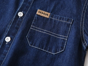 Detailed macro view of denim shirt chest pocket with a brown leather decorative tag