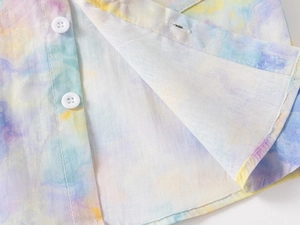 Close-up of kids tie-dye shirt showing white buttons and colorful pastel fabric texture