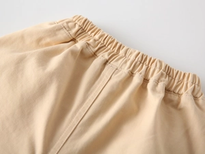 Detail view of beige kids elastic waistband with neat stitching and cotton texture
