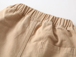 Detail of khaki cotton trousers showing elastic waistband and back square pocket
