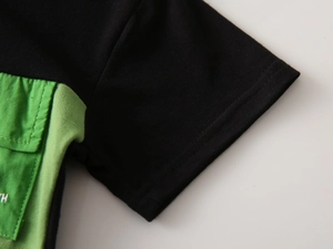 Close-up of black pique cotton polo shirt with contrast green pocket and stitching