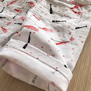 Detailed close-up of white cotton shorts with red pattern on rustic wood surface