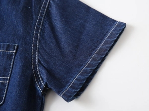 Detail of dark blue denim shirt with durable double-stitched seams and side pocket edge