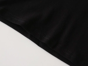 Macro shot of durable double-needle stitching on the hem of a black cotton kids' polo shirt