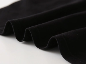 Macro detail of soft black knit fabric and fine stitched hemming on a children's polo shirt