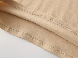 Close-up of khaki cotton polo shirt hem showing reinforced double-stitch sewing detail