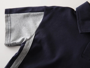 Macro detail of navy cotton polo shirt showing grey sleeve stitching and pique texture