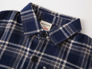 Detail of blue plaid kids shirt showing flannel texture, collar, and brand label