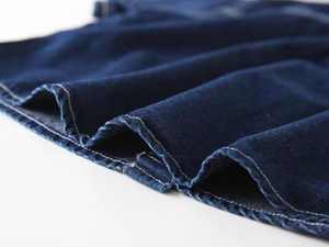 Detail of dark blue denim fabric with contrast white stitching and premium texture