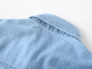 Detailed macro view of light blue denim shirt collar and premium stitching quality