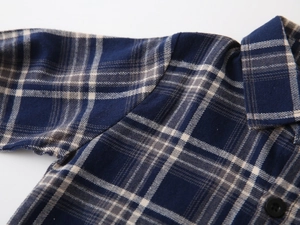 Macro view of blue plaid flannel shirt detailing collar stitching and dark button