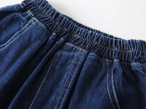Detailed macro view of dark blue denim shorts featuring elastic waistband and dual stitching