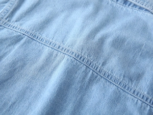 Detailed macro view of light blue denim fabric with double needle stitching