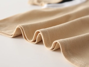Close-up of beige knitted polo shirt showing fine texture and durable double-stitch hem