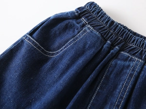 Detailed macro view of dark blue denim shorts with elastic waistband and contrast stitching