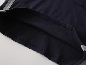 Close-up of navy knit polo shirt hem with gray decorative side tape and neat stitching