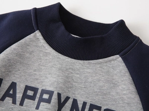 Detail of boys fleece sweatshirt showing HAPPYNESS print and blue ribbed crew neck