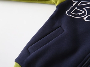 Détail de la veste polaire enfant avec poignet côtelé vert et couture de poche