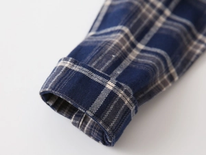 Detailed close-up of flannel plaid shirt cuff featuring double stitching and soft texture
