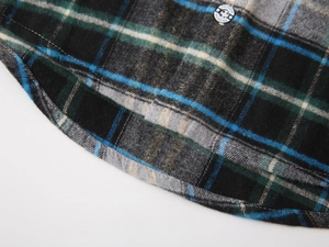 Détail de l'ourlet incurvé et bouton gravé de mode sur chemise à carreaux enfant