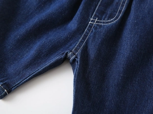 Detail view of deep blue denim fabric with reinforced double stitching on kids trousers