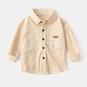 Detailed close-up of beige corduroy kids shirt showing button-up front and chest pocket