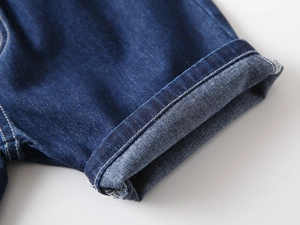 Detail of dark blue denim shorts with folded hem and durable reinforced stitching