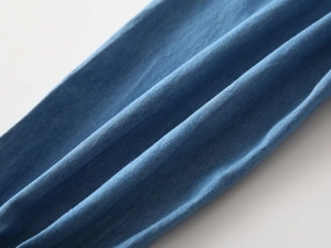 Close-up of lightweight blue denim fabric texture and soft pleats on children trousers