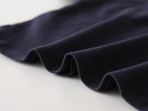 Macro shot of navy blue cotton fabric with detailed double-needle stitching on the hem