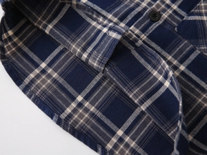 Detail of navy blue plaid shirt hem featuring high-quality stitching and round button