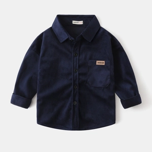 Detail of blue corduroy texture and leather 'DESIGN' label on boys' long-sleeve shirt