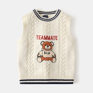 Detail of cable knit pattern and brown bear motif on cream kids knitted sweater vest
