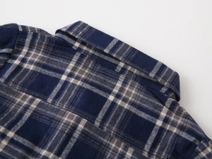 Detailed close-up of navy and beige plaid flannel shirt collar with fine stitching