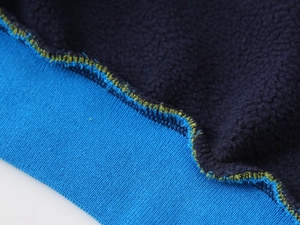 Détail des poignets en tricot et doublure polaire bleue épaisse de la veste de baseball