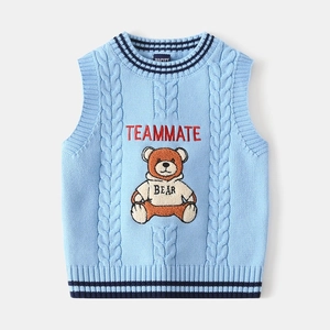 Detail of light blue cable knit kids vest featuring a fuzzy bear and TEAMMATE embroidery