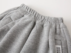 Dettaglio dei pantaloni grigi per bambini con ampia fascia elastica e etichetta tessuta
