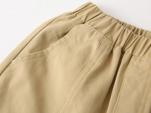 Detailed close-up of khaki cotton trousers featuring elastic waistband and reinforced stitching