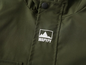 Detail of olive green jacket featuring matte black snaps and a mountain peak embroidery patch